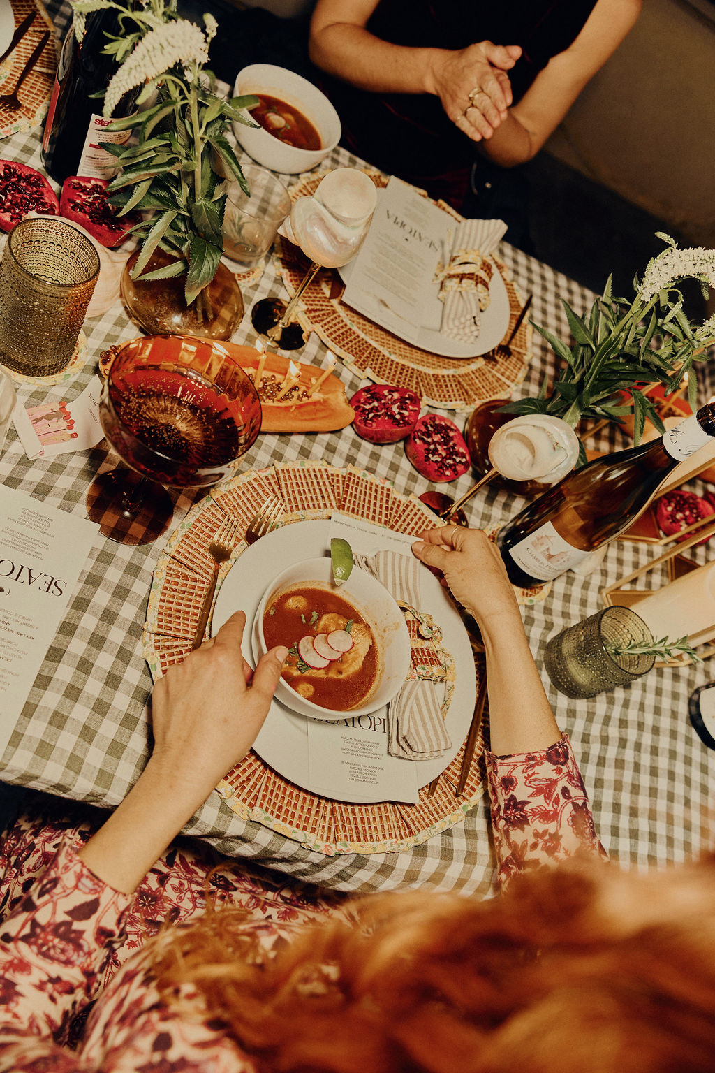 Overhead shot of guests being served a chilled soup course on a gingham table